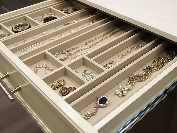 A drawer with organizing dividers full of jewelry.